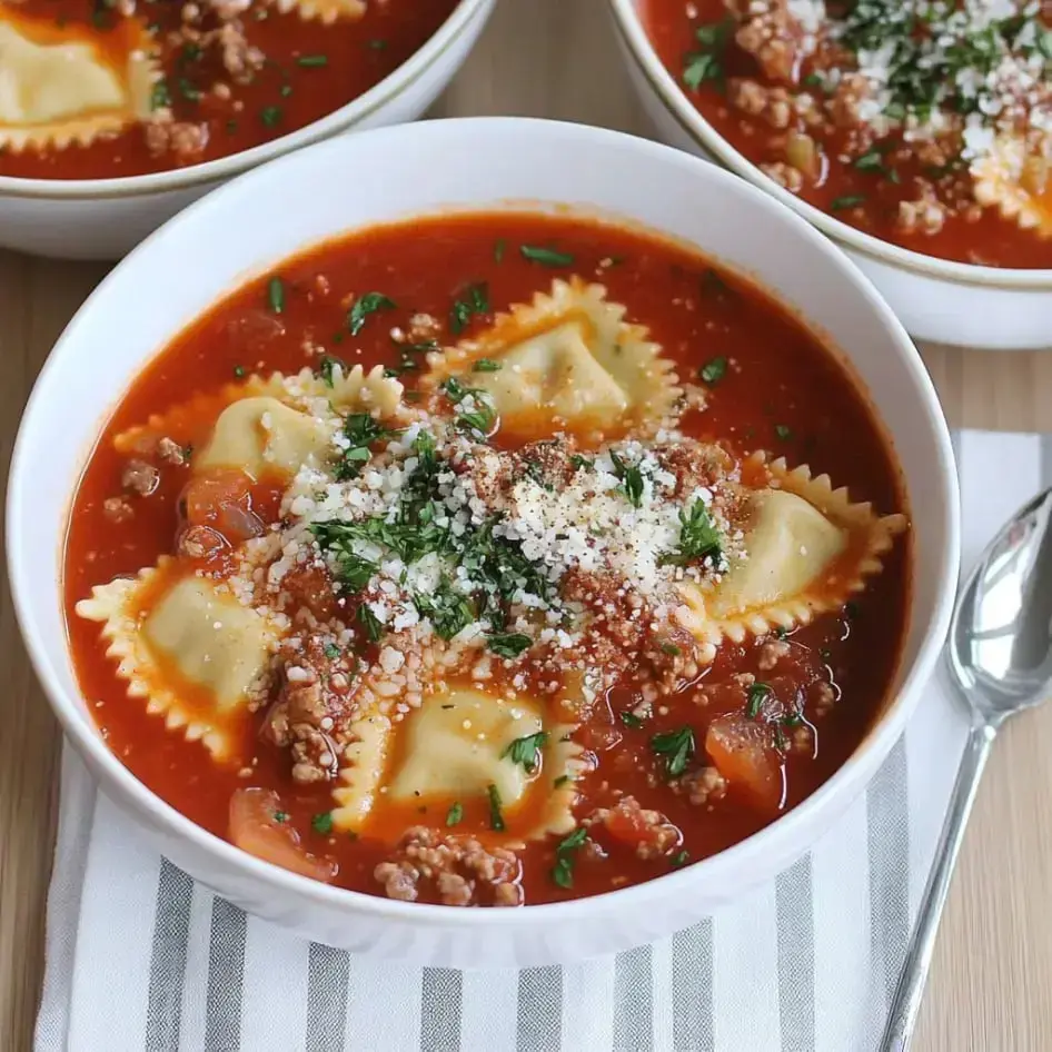 A comforting bowl of beef ravioli soup with tomato broth, sprinkled with parsley and cheese.