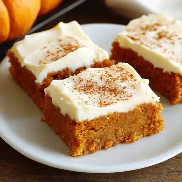 Frosted pumpkin bars on a plate with cinnamon sprinkled on top.