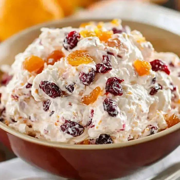 A creamy fruit dip with cranberries and dried apricots in a bowl.