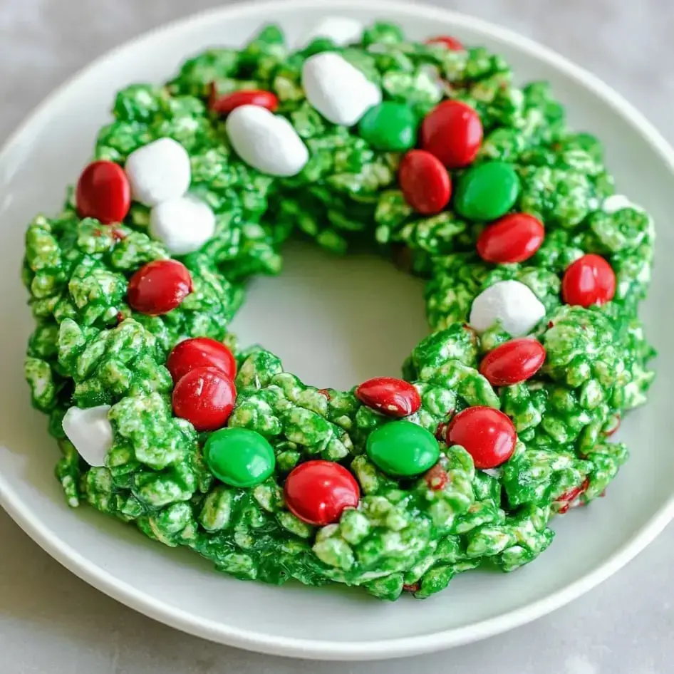 Bright green cornflake wreaths with candies and marshmallows sitting on a plate.