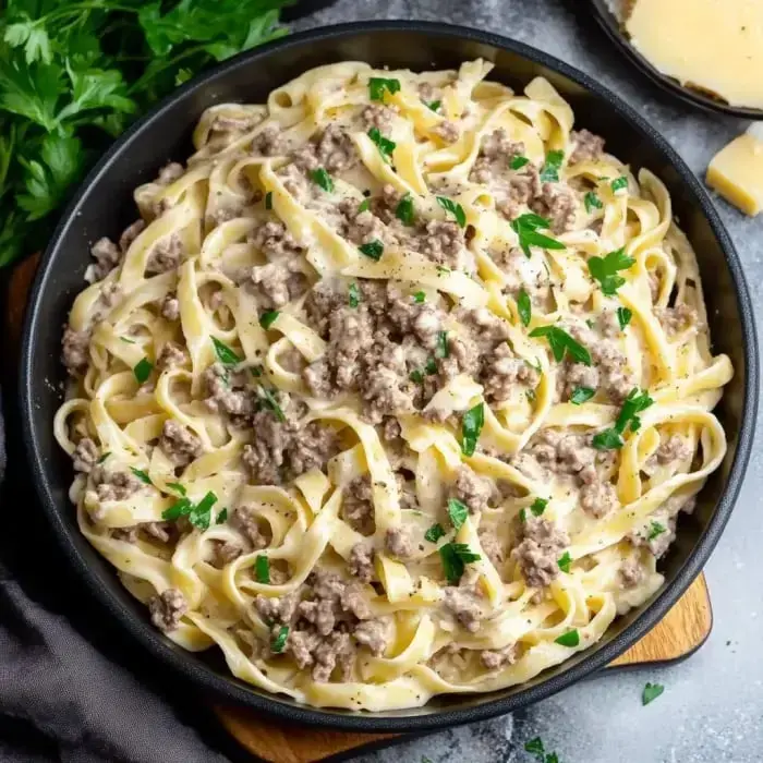 A bowl packed with extra-creamy noodles, seasoned meat, and a hit of fresh green parsley.
