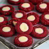 A plate of red sparkly cookies with white creamy middles, a few cookies look partially eaten.