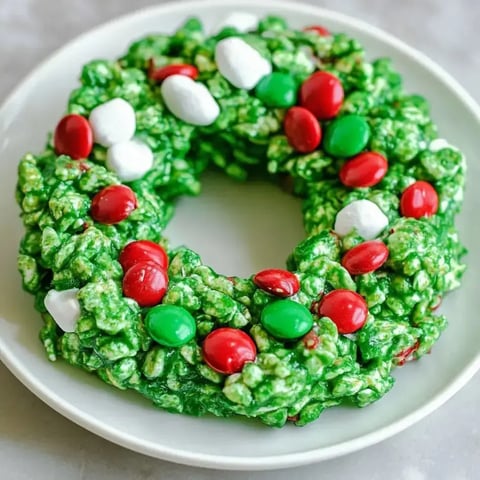 Bright green cornflake wreaths with candies and marshmallows sitting on a plate.